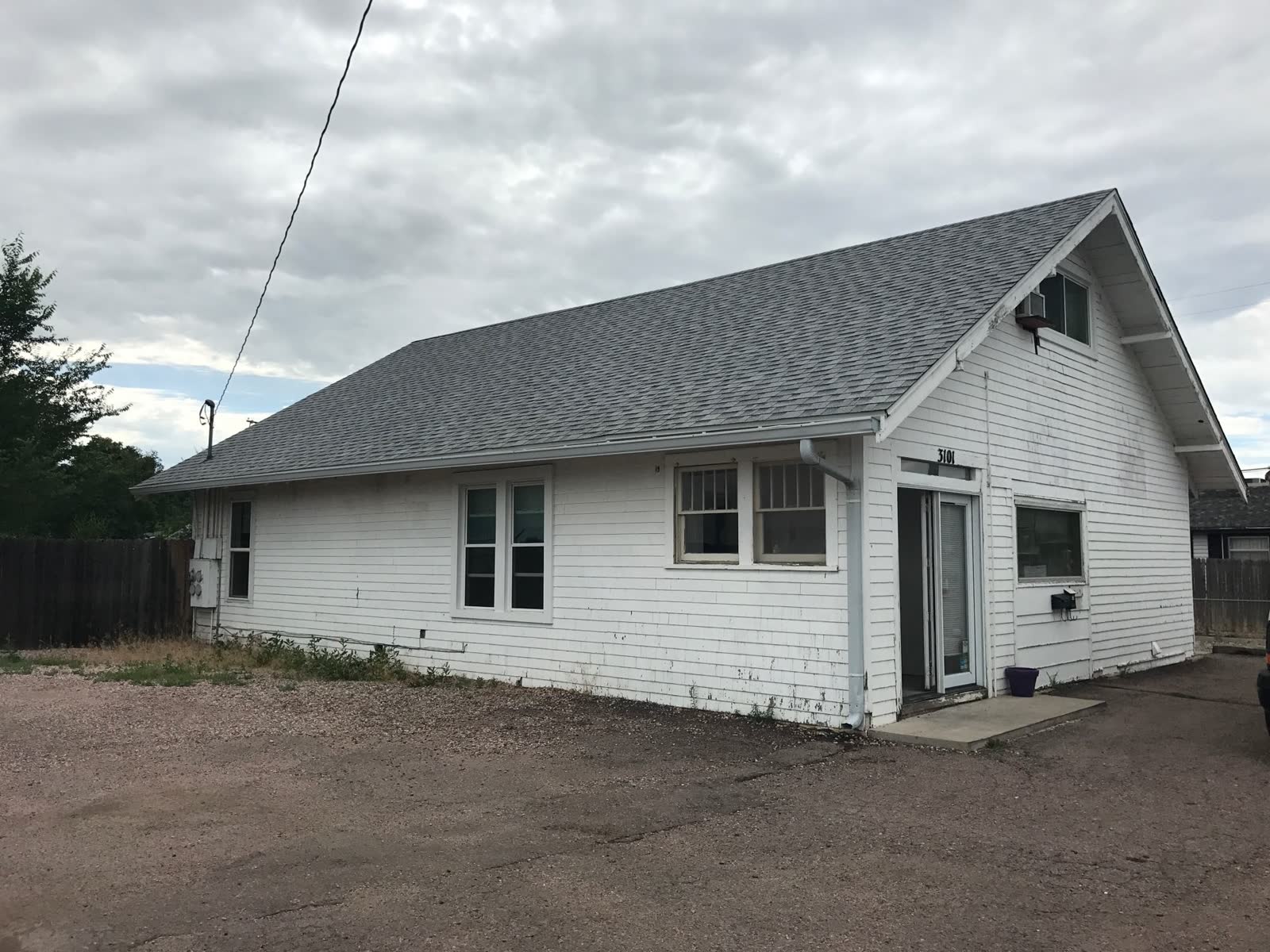 Before: aging white wood-clad home with peeling paint