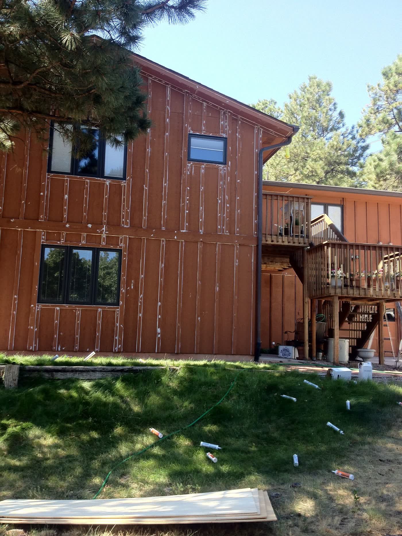 Before: faded redwood-stained board-and-batten home with prep marks
